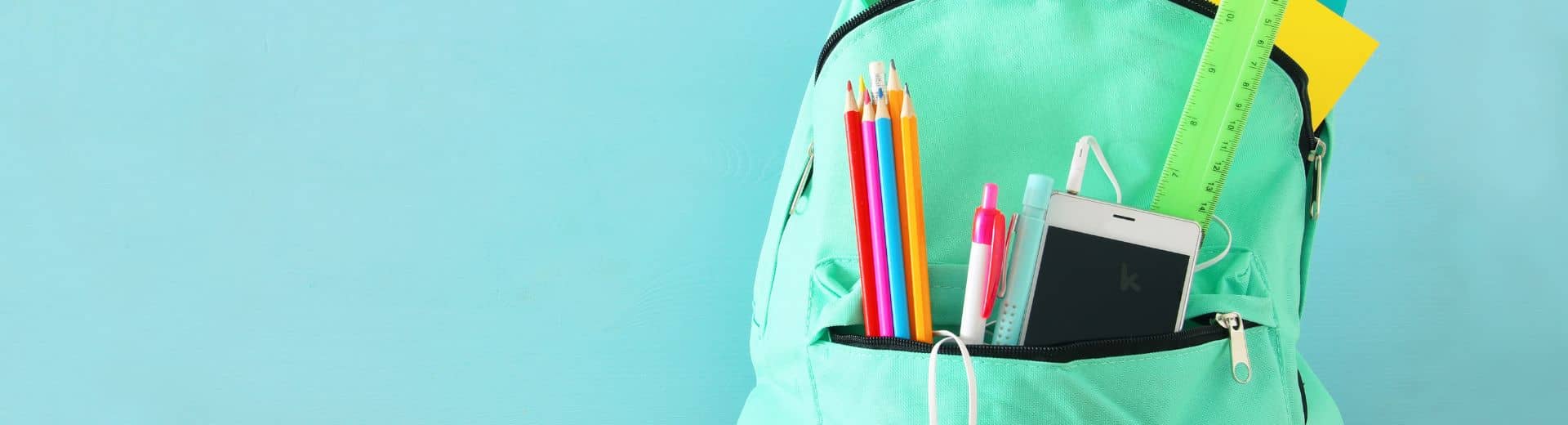 Backpack filled with school supplies on a light blue background